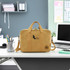A yellow kraft paper satchel with handles and a shoulder strap, featuring a logo, sitting on a desk.