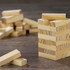 A set of small wooden blocks in light wood tones, stacked to form a tower, with additional blocks scattered nearby.