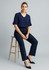 A woman sits on a stool wearing navy slacks and a navy top, paired with matching heels. The outfit has a modern design.