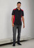 A unisex polo shirt in black with red side panels, featuring short sleeves and a logo. Styled with grey jeans.