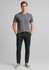 A model wearing black tapered stretch chino pants paired with a grey t-shirt and grey sneakers.