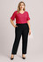A model wearing a pink top and black adjustable waist pants, styled with a relaxed fit. The outfit features a logo.
