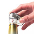 A drink bottle opener featuring a shiny silver magnet with a button badge design is being used to open a bottle.