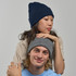 A navy beanie on a woman and a grey beanie on a man, both styled casually. The image features a logo on the beanies.