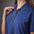 A close-up of a woman's navy polo shirt featuring a collar and button placket, with a logo on the chest.
