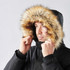 A black parka jacket featuring a fur-lined hood, worn by a man adjusting the hood around his face.