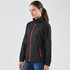 A black rain jacket with a red zip, featuring a high collar and side pockets, displayed on a model.