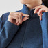 A blue women's 1/4 zip pullover featuring a high collar and a zipper detail, worn by a person adjusting it.