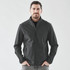 A man wearing a black softshell jacket with a zip front and side pockets, standing against a plain background.