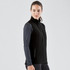 A black softshell vest with a zip front, worn over a long-sleeve top. It features a side pocket and has a logo.