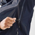 A hand zips up a navy blue rain jacket featuring a sleek design and a logo.