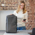 A grey Swissdigital Arosa Backpack with a logo, placed beside a laptop, while a person is using a smartphone.