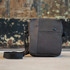 A grey shoulder bag with a smooth texture and a strap, featuring a small logo.