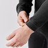 A close-up of a person adjusting the cuff of a black long-sleeve Henley shirt with a textured fabric.