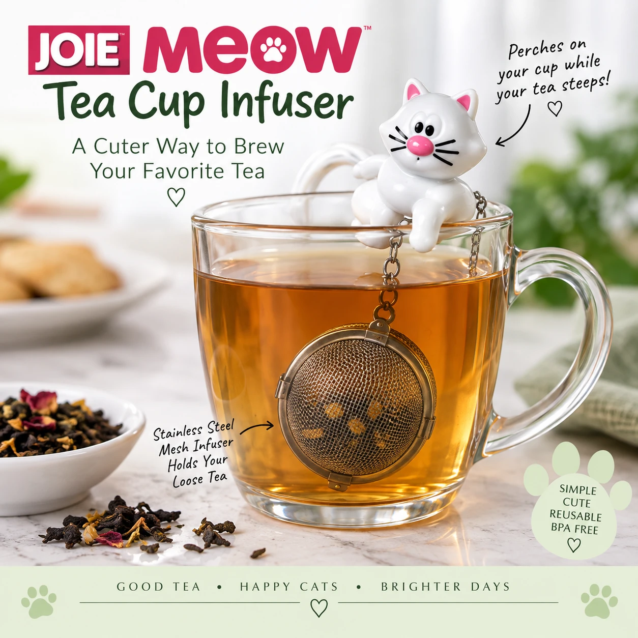 JOIE MEOW Cat Tea Cup Infuser shown in use with the white cat perched on the rim of a glass mug while the reusable stainless steel mesh tea ball hangs in the hot water below. The image demonstrates how the novelty cat infuser holds loose leaf tea while it steeps.