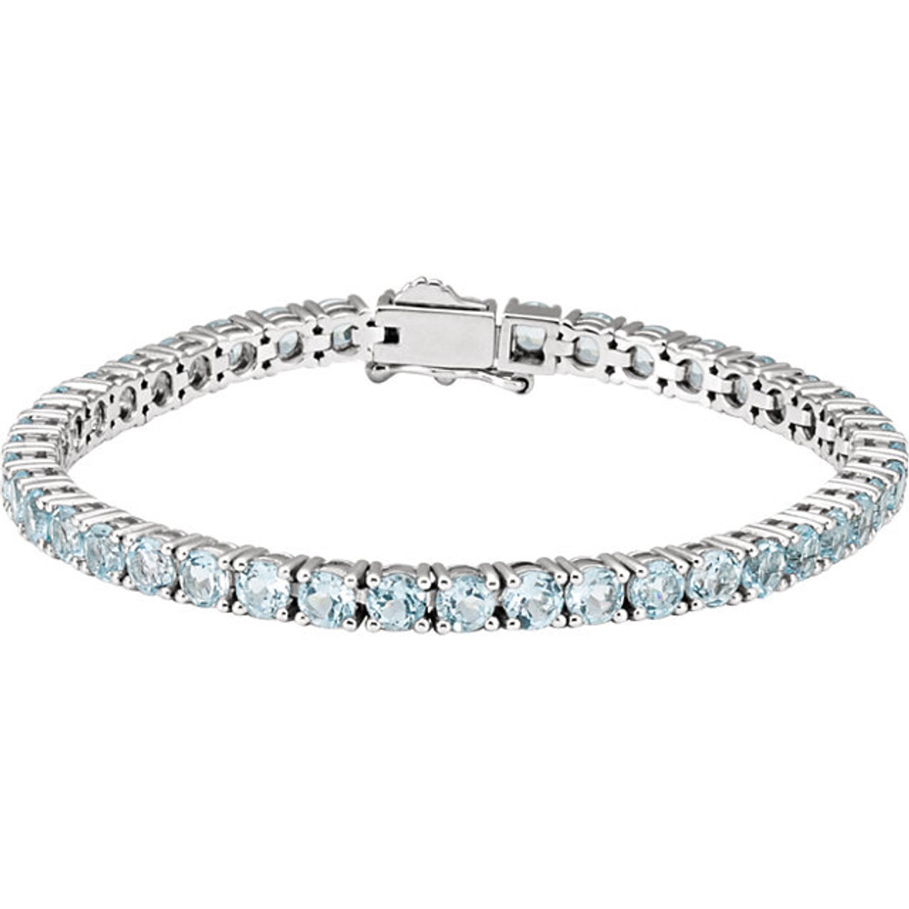 This 14kt white gold line bracelet features forty three 4mm genuine and natural blue topaz. The colored precious gemstones are set in a prong setting.