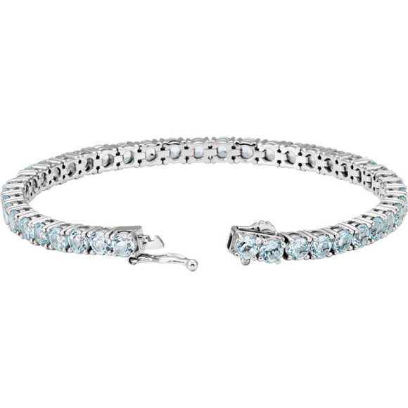 This 14kt white gold line bracelet features forty three 4mm genuine and natural blue topaz. The colored precious gemstones are set in a prong setting.