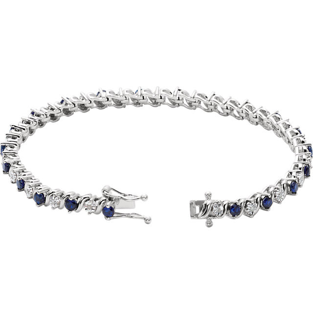 This 14kt white gold bracelet features twenty one 2.75mm created blue sapphires accented by 21 brilliant cut round diamonds of H-J Color and I3 Clarity. The colored precious gemstones and shiny diamonds are set in a prong setting.