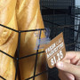 Wire shelving sign holder with signage being attached next to fresh baguettes.