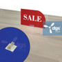 cheap plastic gripper sign holder with adhesive back displaying a retail sale sign at a convenience liquor store