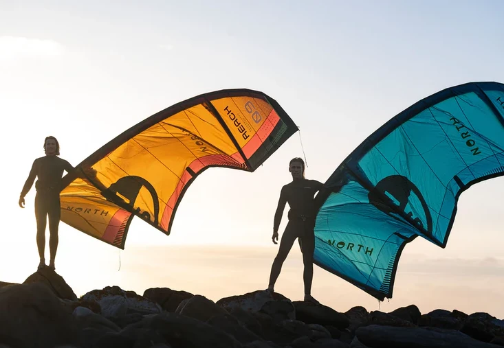 Two kitesurfers holding North kites