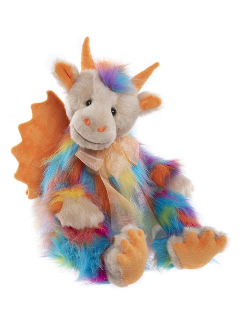 A rainbow multicoloured fluffy dragon plush toy sits upright against a white background, featuring orange horns, wings, claws, and a sheer ribbon bow around its neck.
