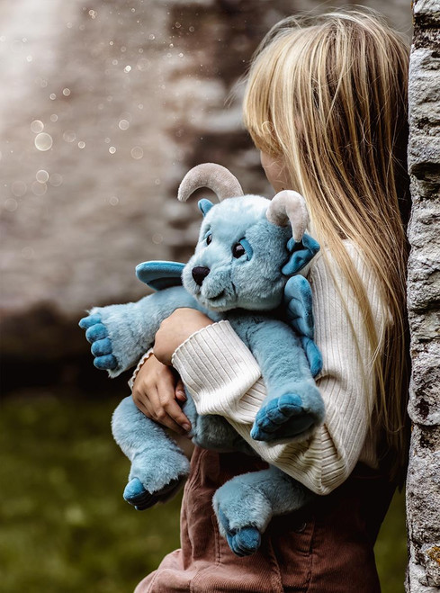 A blue-grey Charlie Bears plush toy combining goat features (curved horns, pointed ears) with butterfly wings, sitting upright against a white background.