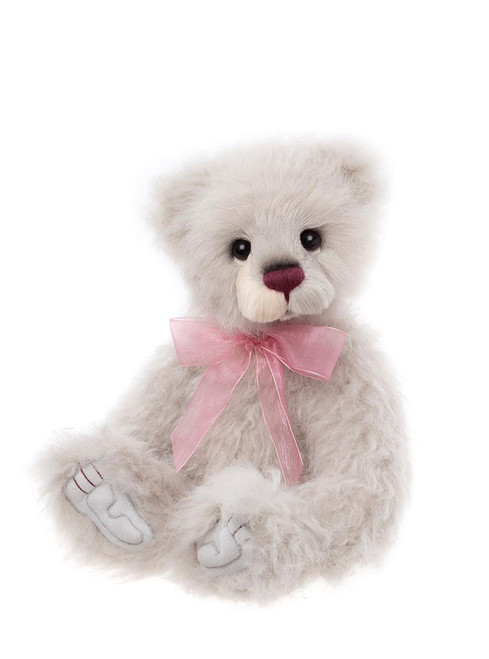 A soft, light grey Charlie Bears teddy bear sits upright against a white background, wearing a sheer pink ribbon bow at its neck, with a mauve nose and white paw pads.