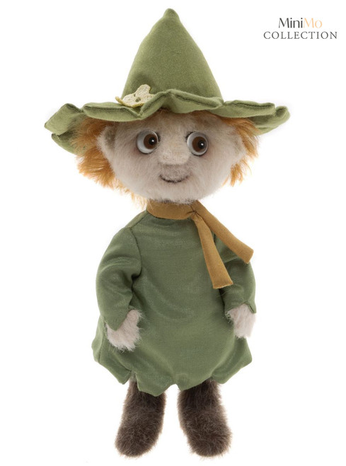A plush teddy bear dressed in a green outfit and matching wide-brimmed witch-style hat, with orange hair, brown eyes, and a mustard yellow scarf, stands upright against a white background.