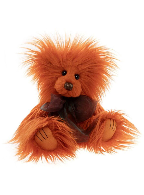 An orange shaggy teddy bear sits upright against a white background, wearing a dark charcoal organza bow tie, with small black eyes and stitched paw details.