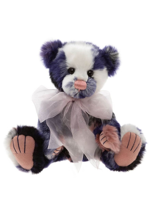 A blue, white, and black patchwork Charlie Bears teddy bear sits upright, wearing a sheer white ribbon bow at its neck, with pink suede paw pads, against a white background.