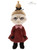A small plush doll stands upright against a white background, wearing a dark red dress with a pink bow collar, black hands and feet, blonde upswept hair tied with a black ribbon, and a grumpy facial expression.