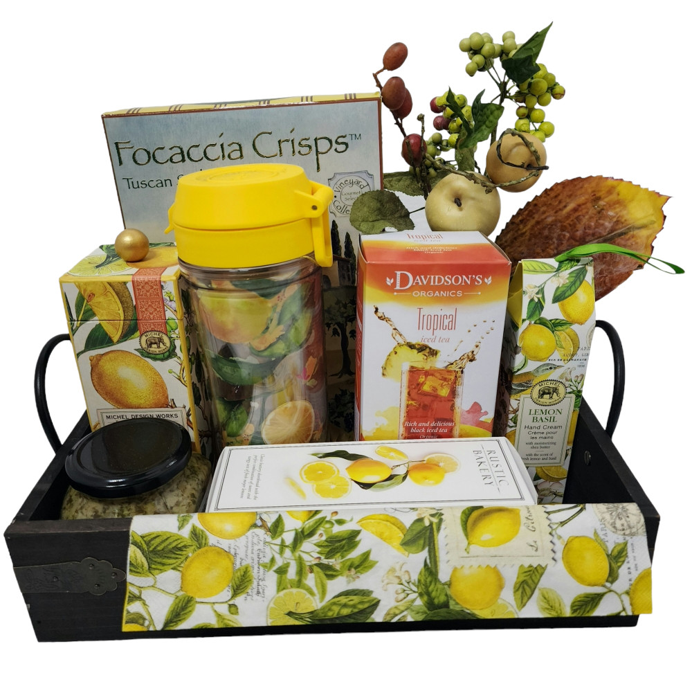 A wood and metal tray filled with Tropical ice tea, a beautiful travel mug to put the ice tea in, Meyer Lemon shortbread cookies, Artichoke Lemon Pesto spread, crackers, body cream, and a luxurious hand cream.