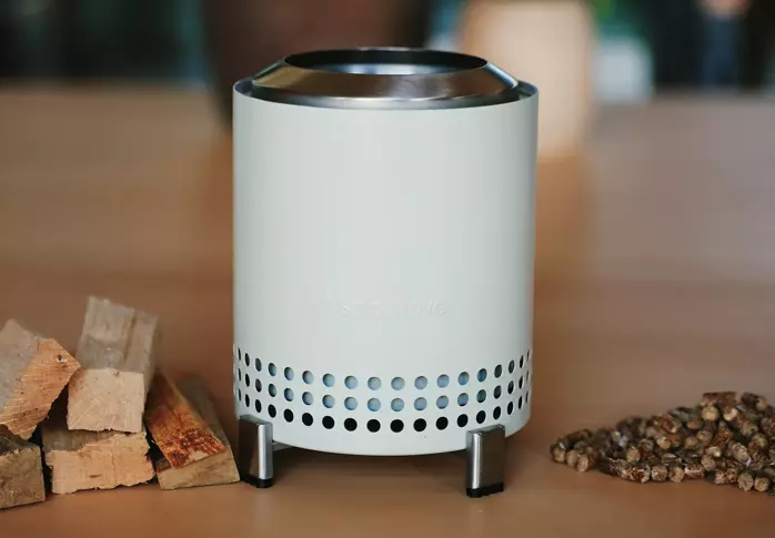 Solo stove with stand next to different fuels: wood chips and wood pellets