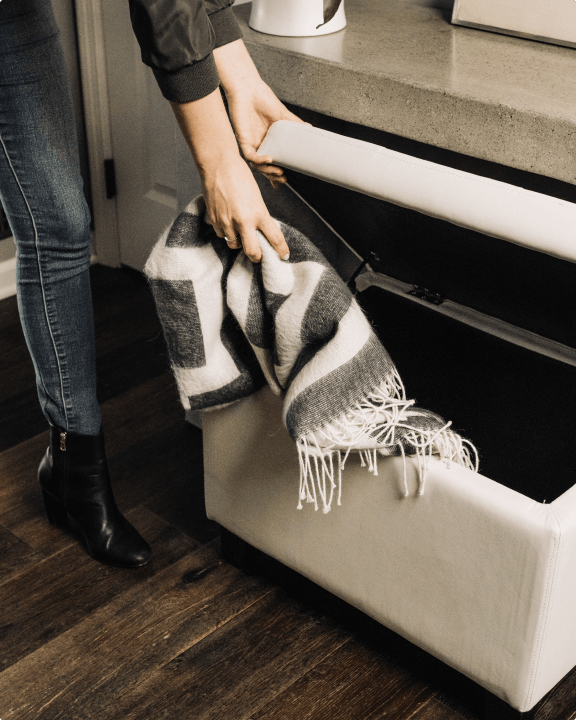 Person putting blanket in ottoman