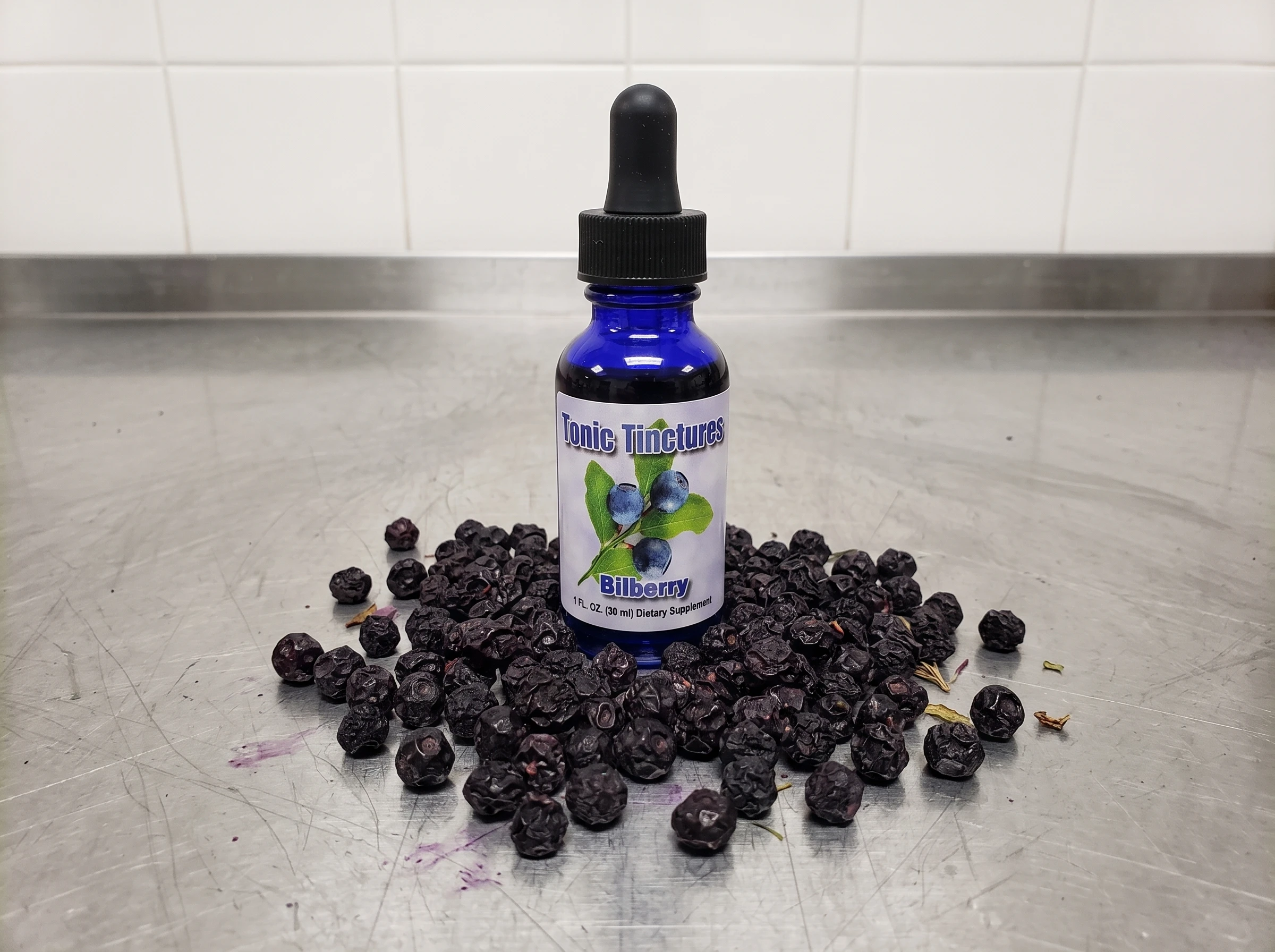 Raw dried bilberries surrounding amber tincture bottle