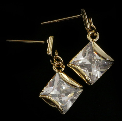 Gold tone cubic zirconia dangle earrings with a diamond shaped stone hanging from a diamond shaped post CZ28