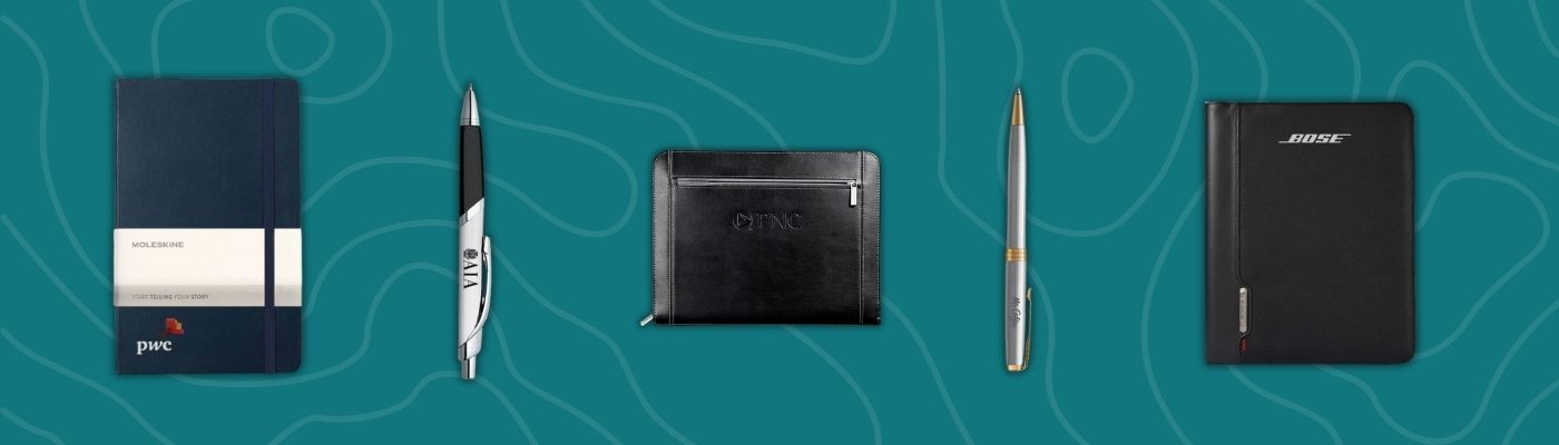 Collection of premium office supplies including Waterman and Parker pens, Moleskine notebook, leather padfolio, and Bose organizer.