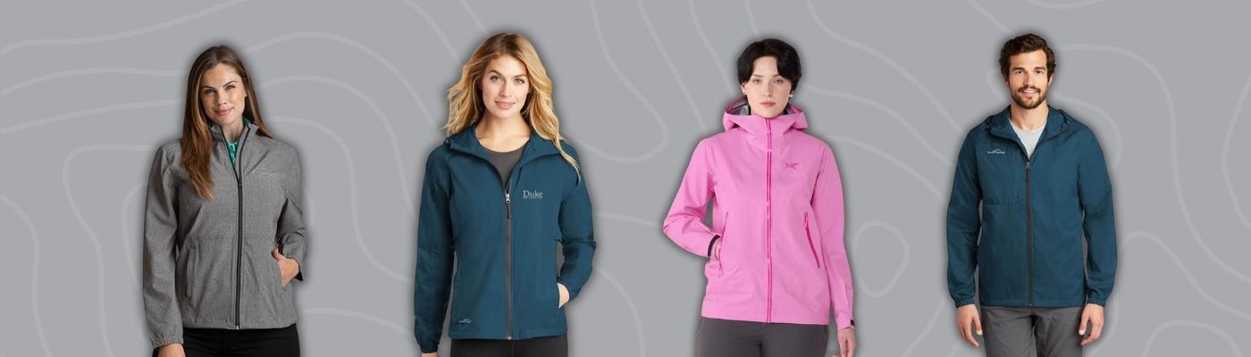 Models wearing custom windbreaker jackets in gray, navy, pink, and teal from brands like Eddie Bauer, Greg Norman, and Arc’teryx, designed as lightweight outer layers for corporate teams.