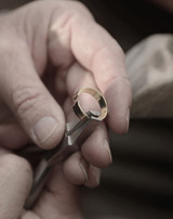 Skilled craftsman holding a resized gold ring, showcasing precise craftsmanship.