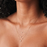 Elegante collar escalonado de oro de 14k con tres diamantes engastados en bisel sobre delicadas cadenas, diseñado para adornar su cuello con belleza, como se ve en una modelo puertorriqueña.