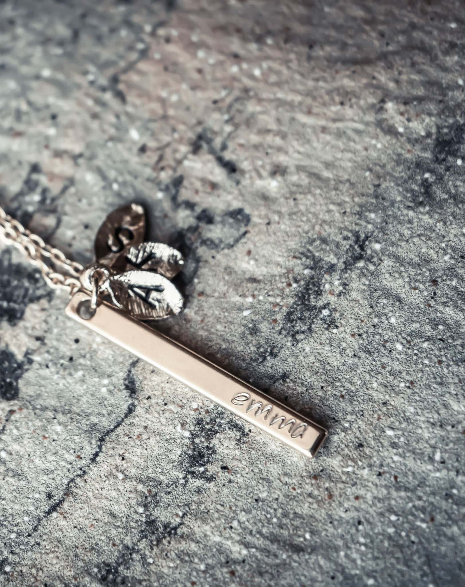 Engraved charm product with intricate detailing, displayed against a rocky backdrop.