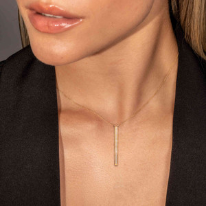 Adorning a clear-skinned Puerto Rican model, the 14k gold drop bar necklace, suspended on a delicate cable chain, features a central diamond-encrusted bar for alluring radiance, perfect when paired with the matching diamond dangle necklace.