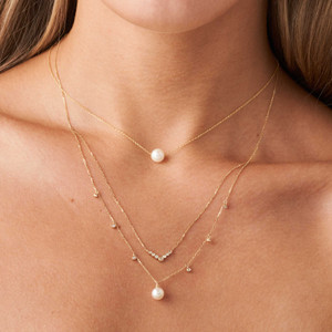 Una modelo de piel clara que lleva en el cuello nuestro Collar de Diamantes y Perlas en Capas, excelente para crear combinaciones apilables.