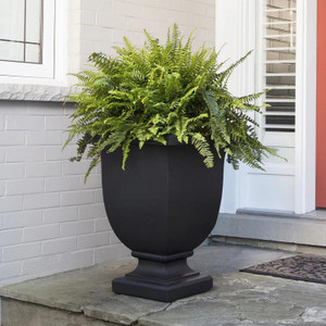 Julian Urn Planter - 2 Sizes, large black decorative urn with lush green fern plant outside on porch near white brick wall and door.