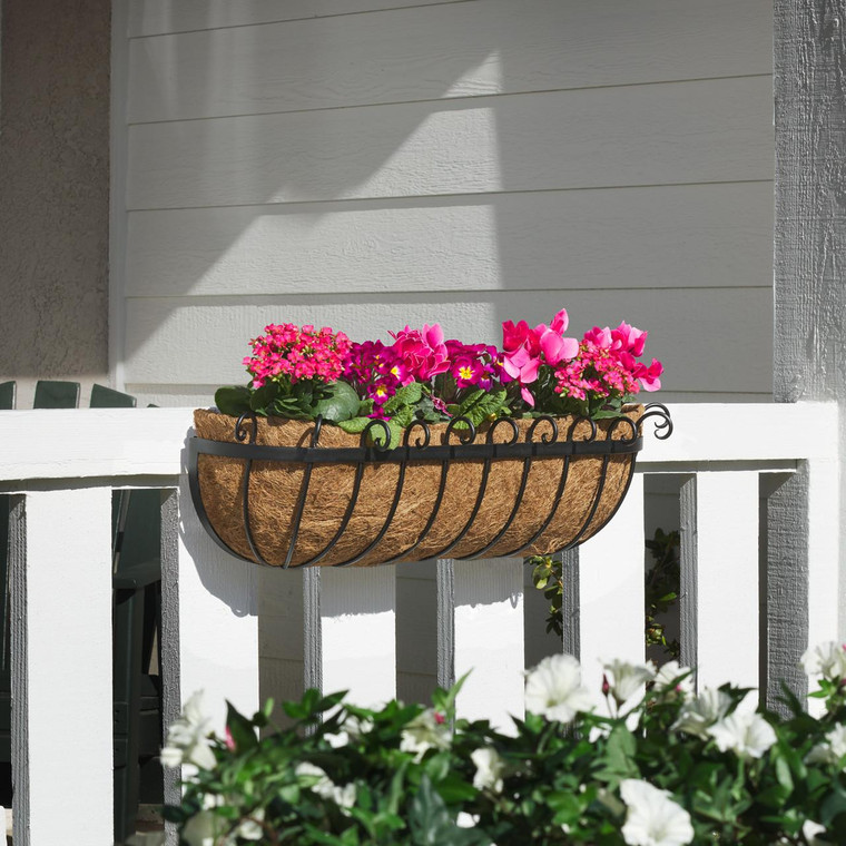 Scroll Hayrack Railing Planter, metal and coconut fiber hanging planter with vibrant pink flowers on a white porch railing.