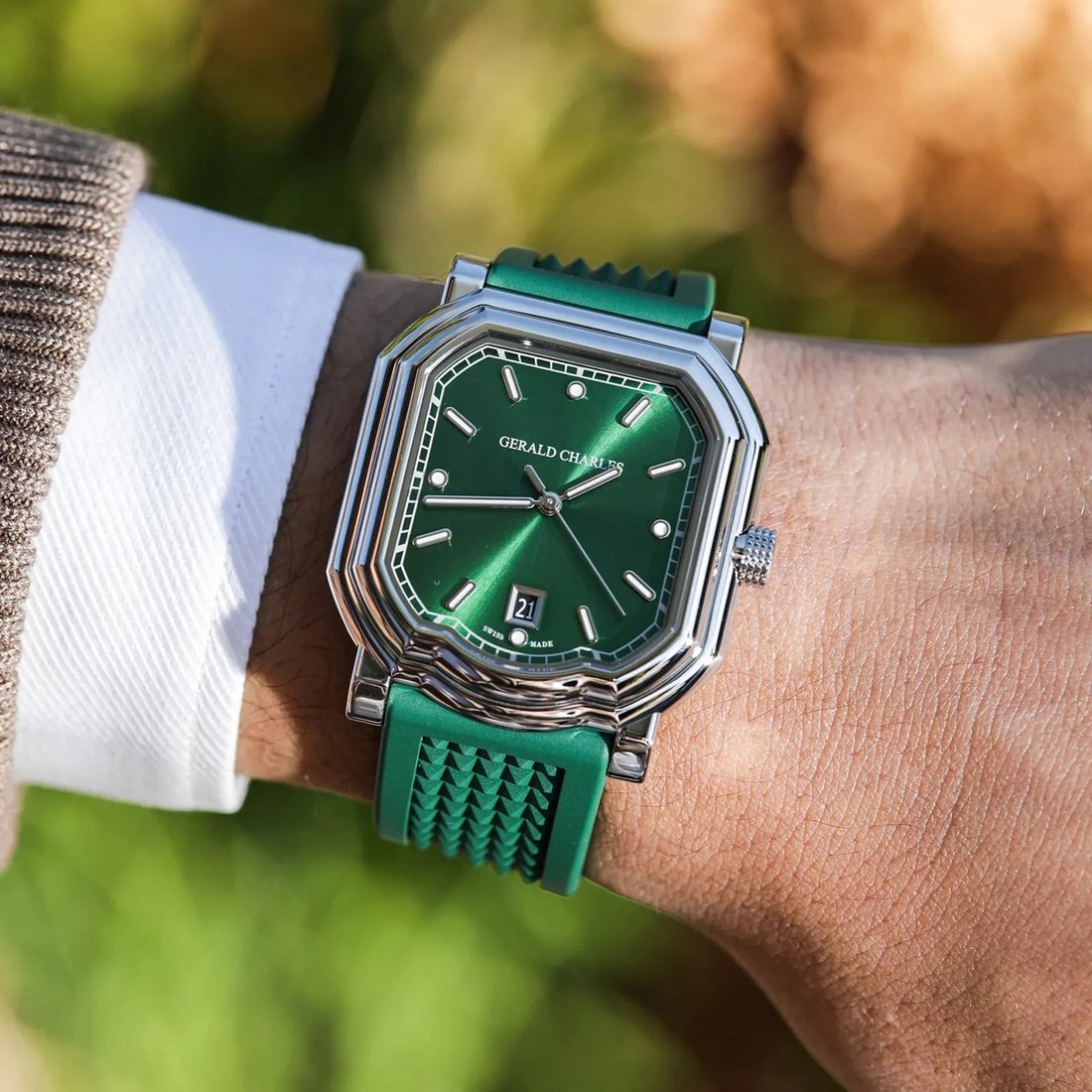 Gerald Charles Maestro 2.0 Ultra-Thin worn on the wrist outdoors against green foliage, sunlight raking across the polished stepped bezel and emerald sunburst dial.