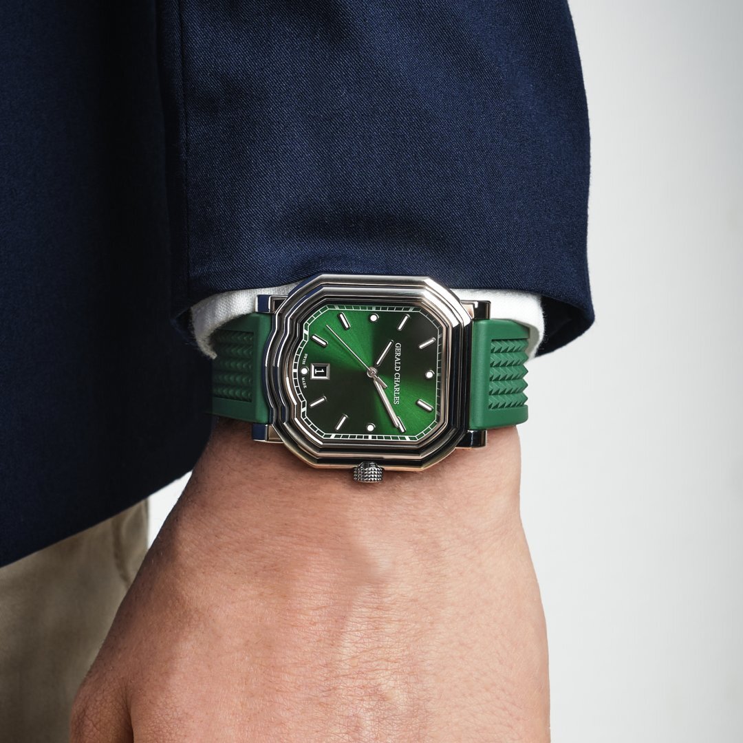 Gerald Charles Maestro 2.0 Ultra-Thin in steel with an emerald green dial, worn on the wrist beneath a white shirt cuff and navy jacket sleeve, seen from the side so the stepped case profile is visible.