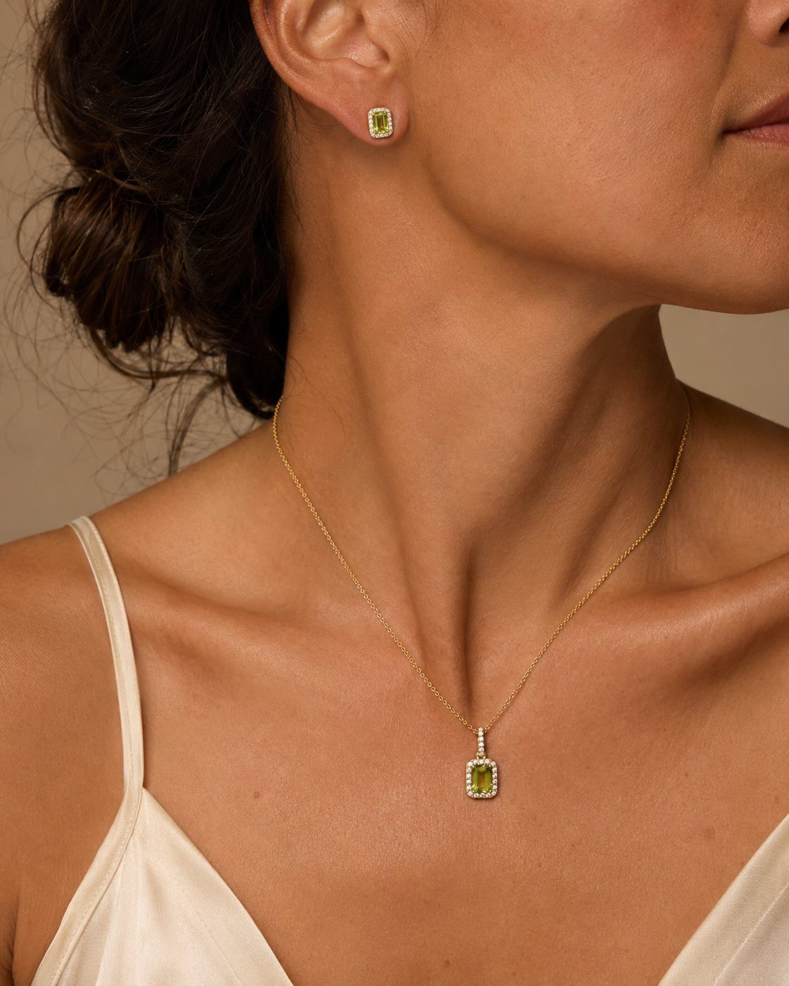 Woman wearing a 14k yellow gold peridot and diamond pendant and matching stud earrings