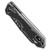 Angled closed view of Heretic Knives Jinn Automatic demonstrating button lock placement, reversible pocket clip design, and textured black carbon fiber handle grip surface.